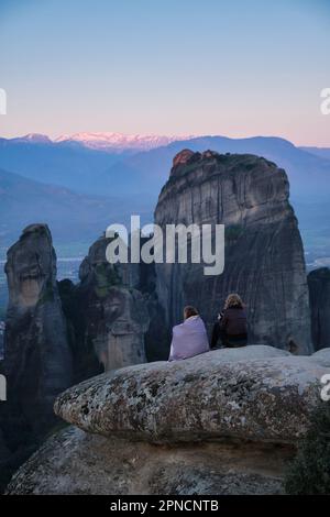 Zwei weibliche Touristen warten auf den Sonnenaufgang über Meteora im Frühling Stockfoto