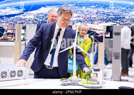 Hannover, Deutschland. 18. April 2023. Robert Habeck (Bündnis 90/die Grünen, 2. von links), Bundesminister für Wirtschaft und Klimaschutz, steht vor einem Modell einer Windturbine während einer Führung durch den Stand von Phoenix Contact auf der Hannover Messe. Dahinter stehen Klaus Hengsbach (l) und Angela Josephs (r), beide von Phoenix Contact. Vom 17. Bis 21. April 2023 findet die weltweit größte Industriemesse statt. Kredit: Michael Matthey/dpa/Alamy Live News Stockfoto