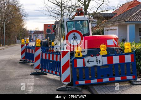 Ein kleiner Traktor, der auf dem Bürgersteig hinter den Absperrungen steht. Kein Fußgängerverkehrsschild. Verkabelung. Stockfoto