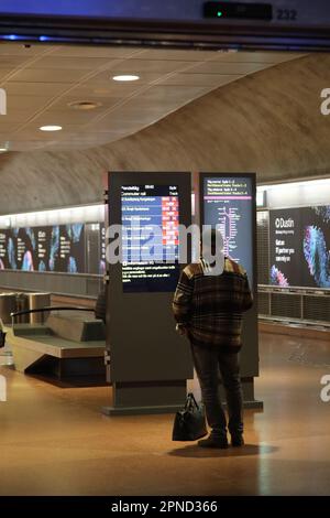 Stockholm, Schweden. 18. April 2023. Ein Passagier überprüft elektronische Fahrpläne an einem Bahnhof in Stockholm, Schweden, am 18. April 2023. Mehr als 80 Prozent der Pendlerzüge, die für die Hauptverkehrszeit am Montagabend in der schwedischen Hauptstadt geplant waren, wurden aufgrund eines Streiks von Zugführern gestrichen, berichten die lokalen Medien. PASSEND ZU „Pendlerzugfahrer Stage Strike in Stockholm“. Gutschrift: Fang Ming/Xinhua/Alamy Live News Stockfoto