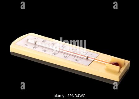 Ein Thermometer zur Messung der Raumtemperatur, Makro, isoliert auf schwarzem Hintergrund. Stockfoto