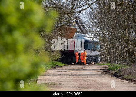 Nahe Abingdon on Thames, Oxfordshire, Großbritannien, 18. April 2023. Eine Besatzung wartet, während Teile einer temporären Straße entladen werden, um Zugang zum Nuneham Viaduct zu schaffen, einer abgelegenen Eisenbahnbrücke über die Themse im ländlichen Oxfordshire, Großbritannien. Die Brücke ist wegen wichtiger Reparaturen für mehrere Monate geschlossen, von April bis mindestens Juni 2023, wodurch die Hauptverbindung von Oxford nach London vollständig getrennt wird. Der südliche Anker der Brücke ist vom Einsturz bedroht und wird seit langem genau überwacht. Die Brücke wurde geschlossen, um die öffentliche Sicherheit zu wahren. Der Zugriff auf die Öffentlichkeit ist während geschlossen Stockfoto