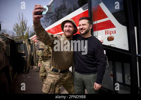 Avdiivka, Ukraine. 18. April 2023. Der ukrainische Präsident Wolodymyr Zelenskyy macht ein Selfie mit einem ukrainischen Soldaten, links, während eines Besuchs an der Front in der Region Donezk am 18. April 2023 in Avdiivka, Ukraine. Zelenskyy besuchte den Scania-Evakuierungsbus und besuchte verwundete Krieger in einem Militärkrankenhaus. Kredit: Pool Photo/Pressestelle Des Ukrainischen Präsidenten/Alamy Live News Stockfoto