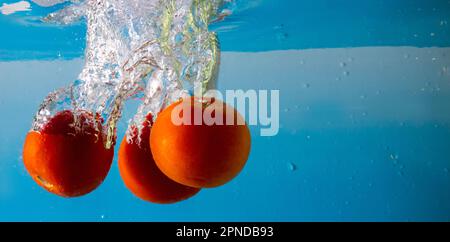 Reife Tomate fällt tief unter Wasser mit einem big Splash. Stockfoto