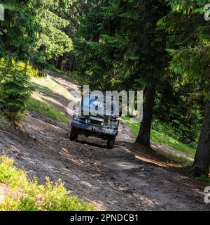 Ein alter Retro-Geländewagen im Vintage-Stil auf einer Schotterstraße im Sommer. Geländewagen Bergsafari Abenteuer Natur Reise Konzept. Stockfoto