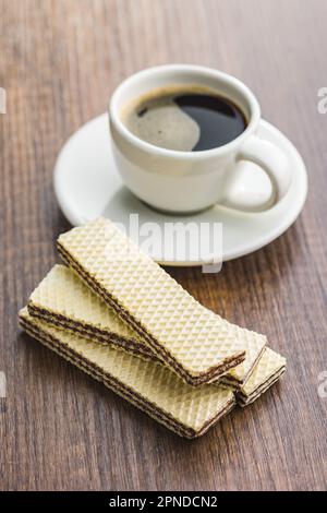 Süße Schokoladentafer und Kaffeetasse auf dem Holztisch. Stockfoto