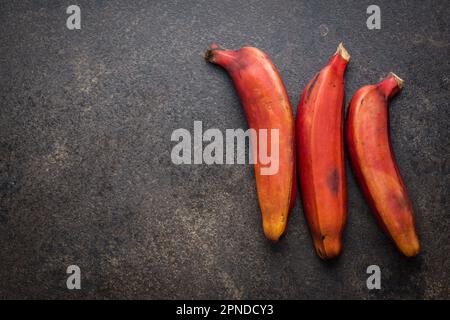 Leckere rote Bananen auf dem schwarzen Tisch. Draufsicht. Stockfoto