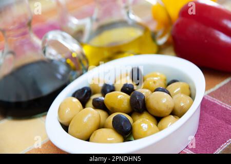 Grüne und schwarze Oliven mit Olivenöl und Balsamico-Essig Stockfoto