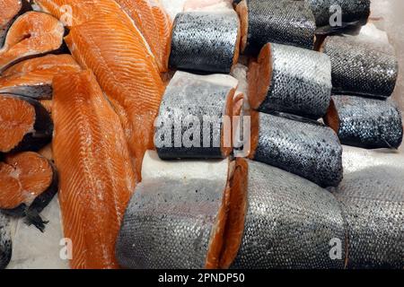 Viele frische, saftige, gekühlte Lachssteaks und rote Fischstücke mit Waage liegen im Laden vor dem Sea Food Store aus nächster Nähe Stockfoto