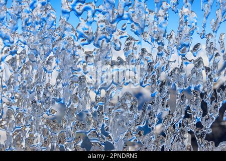 Gefrorenes Wasser tropft auf das Winterfenster. Abstrakter Hintergrund Stockfoto