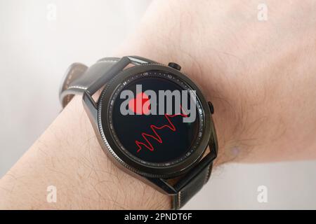 MOGILEV, WEISSRUSSLAND - 05. APRIL 2023: Männliche Hand mit Samsung Galaxy Watch3. Anzeige der Herzfrequenz am Handgelenk. Weltgesundheitstag. Schließen. Stockfoto