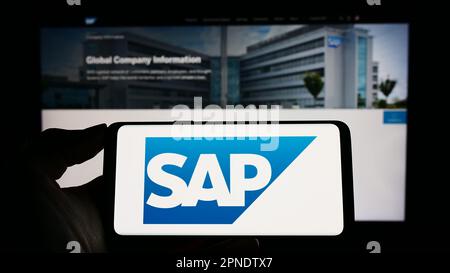 Person, die ein Smartphone mit dem Logo des deutschen Softwareunternehmens SAP SE auf dem Bildschirm vor der Website hält. Konzentrieren Sie sich auf das Display des Telefons. Stockfoto