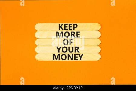 Mehr Geld behalten Symbol. Konzeptbegriffe halten mehr von Ihrem Geld auf Holzstäbchen. Schöner orangefarbener Tischhintergrund. Das Geschäft hält mehr davon Stockfoto