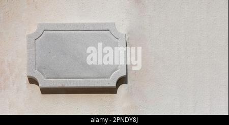 Leeres Marmorschild an der Wand. Weißes leeres Etikett, Kopierbereich, Vorlage. Stockfoto