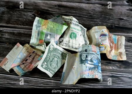 Zerknitterte und zerknitterte Kuwaiti-Banknote, Vierteldollar-Dinar-Banknote und 1 US-Dollar-Bargeld, Geldinflation und Wertverlust, d Stockfoto