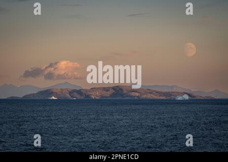 Vollmond geht in der Dämmerung über einem Eisberg an der Küste von Labrador in der Nähe des Saglek Fjord in Nordkanada auf. Stockfoto