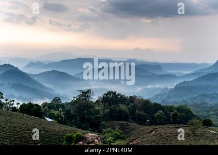 Eine herrliche Landschaft mit riesigen Bergen, bedeckt von flauschigen Wolken und schimmerndem Tau, verzaubert die Sinne. Stockfoto