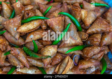 Frisch zubereitete Samosa zum Servieren mit einer frischen grünen Chilischote. Stockfoto