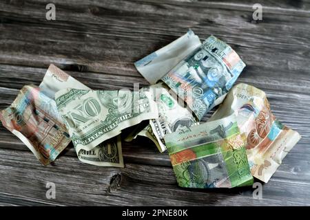 Zerknitterte und zerknitterte Kuwaiti-Banknote, Vierteldollar-Dinar-Banknote und 1 US-Dollar-Bargeld, Geldinflation und Wertverlust, d Stockfoto