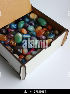 Sperrholzbox mit offenem Deckel, zur Hälfte mit durchsichtigen farbigen Mineralsteinen gefüllt Stockfoto
