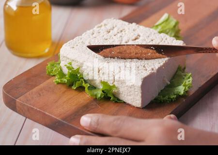 Tofu auf einem Schneidebrett auf dem Tisch schneiden Stockfoto