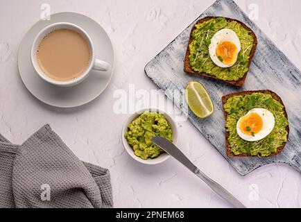 Essensfotografie von Sandwich mit Roggenbrot, Ei, Avocado, Kressensalat, Tee, Kaffee, Milch, Limette, Toast, Frühstück, Diät Stockfoto