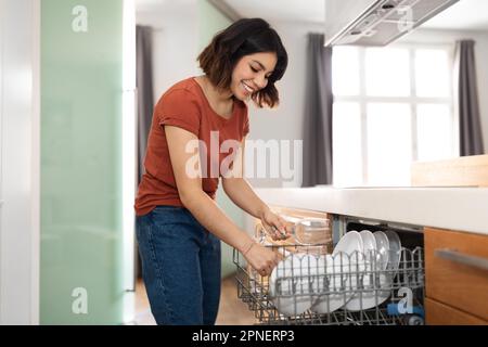 Hausarbeit-Konzept. Lächelnde Nahost-Lady Mit Geschirrspülmaschine In Der Küche Stockfoto