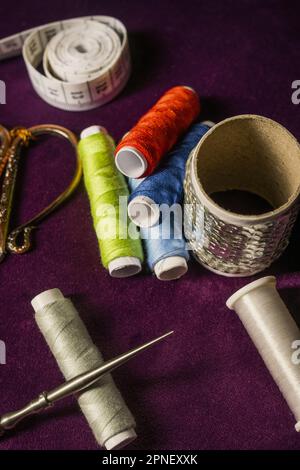 Nähutensilien, Scheren, Garnrollen, auf dunkellila Samtstoff gelegt Stockfoto