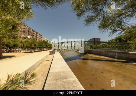 Blick auf eine grün bemalte Fußgängerbrücke aus Stahl über den fluss manzanares in Madrid an klaren Tagen Stockfoto