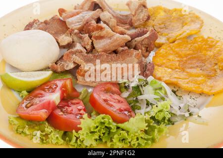 Kolumbianisches Essen, Gebratener Chicharron Begleitet Von Salat, Patacon Und Arepa. Stockfoto