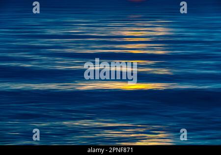 Sonnenlicht, das in einer ruhigen Wasseroberfläche reflektiert wird Stockfoto