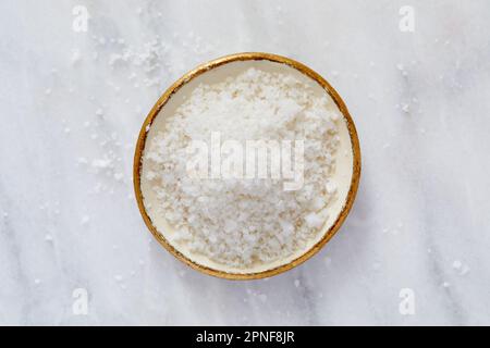 Blick von oben auf Meersalz in Schüssel auf Marmoroberfläche Stockfoto