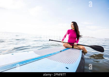 Eine Frau, die auf dem Paddleboard sitzt Stockfoto