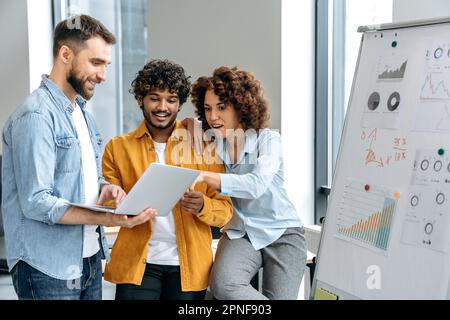 Erfolgreiche, motivierte, multiethnische Kollegen, stehen in der Nähe von Markierungsbrettern im Büro, entwickeln von Neugründungen, Planen von Strategien, Überdenken von Ideen, Risikoanalyse, Kommunizieren. Zusammenarbeit, Teamarbeit Stockfoto
