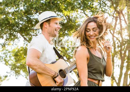 Glückliche Frau und Mann, die im Sommer Spaß im Park haben Stockfoto