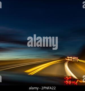 Verschwommenes Bild von Lichtern auf der Autobahn in der Dämmerung Stockfoto