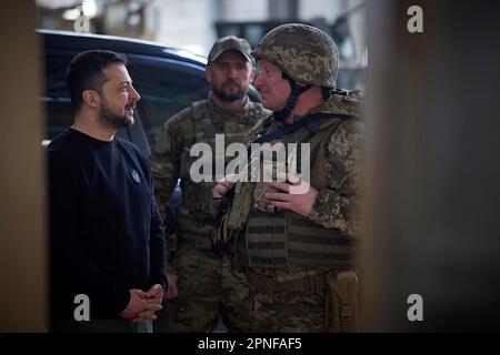 Kherson, Ukraine. 19. April 2023. Zeigt, wie der ukrainische Präsident Wolodymyr Zelensky (L) während seines Besuchs in der schwer beschießten Frontstadt Avdiivka in der Region Donezk inmitten der russischen Invasion der Ukraine am Dienstag, den 18. April 2023, Soldaten verlieh. Foto: Pressestelle des ukrainischen Präsidenten/UPI. Kredit: UPI/Alamy Live News Stockfoto