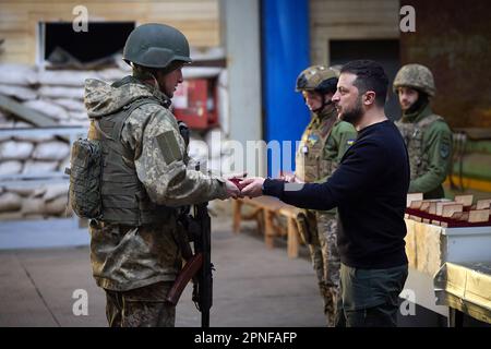 Kherson, Ukraine. 19. April 2023. Zeigt, wie der ukrainische Präsident Wolodymyr Zelensky (R) während seines Besuchs in der schwer beschießten Frontstadt Avdiivka in der Region Donezk inmitten der russischen Invasion der Ukraine am Dienstag, den 18. April 2023, Soldaten verlieh. Foto: Pressestelle des ukrainischen Präsidenten/UPI. Kredit: UPI/Alamy Live News Stockfoto