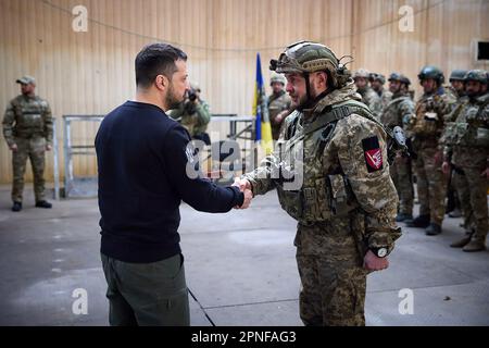 Kherson, Ukraine. 19. April 2023. Zeigt, wie der ukrainische Präsident Wolodymyr Zelensky (L) während seines Besuchs in der schwer beschießten Frontstadt Avdiivka in der Region Donezk inmitten der russischen Invasion der Ukraine am Dienstag, den 18. April 2023, Soldaten verlieh. Foto: Pressestelle des ukrainischen Präsidenten/UPI. Kredit: UPI/Alamy Live News Stockfoto