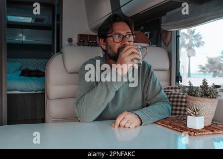 Mann sitzt im Wohnmobil und trinkt Tee Stockfoto