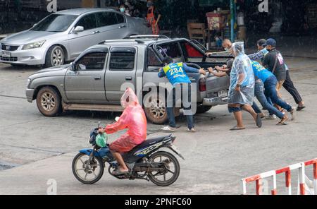 SAMUT PRAKAN, THAILAND, 07 2022. Okt. Männer helfen, ein beschädigtes Auto auf die Straße zu schieben Stockfoto