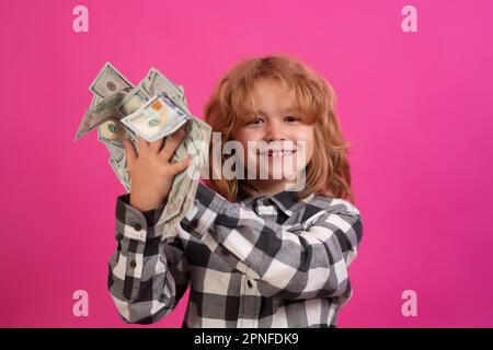 Amerikanische Träume. Das Kind zeigt Dollarscheine, träumt von Reichen vor einem isolierten rosa Studiohintergrund. Stockfoto