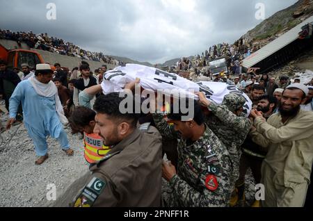 Khyber Agency, Khyber Pakhtunkhwa, Pakistan. 18. April 2023. Anwohner und Rettungsteams entfernen die Leiche einer Person, die nach einem Erdrutsch getötet wurde, der auf eine Autobahn in der Nähe der Grenzstadt Torkham, Pakistan, am Dienstag, den 18. April 2023, traf. Vor Dienstanbruch des Morgens stürzte ein massiver Erdrutsch auf einen wichtigen Highway in der Nähe der Grenzstadt Torkham im Nordwesten Pakistans, wobei mehrere Lastwagen begraben und einige Menschen verletzt wurden und drei Polizisten und Rettungsbeamte getötet wurden. (Kreditbild: © Hussain Ali/Pacific Press via ZUMA Press Wire) NUR REDAKTIONELLE VERWENDUNG! Nicht für den kommerziellen GEBRAUCH! Stockfoto