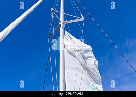 Segel setzen auf einer Yacht. Junger Mann Captan hebt das Segel einer Katamaranjacht während der Fahrt Stockfoto