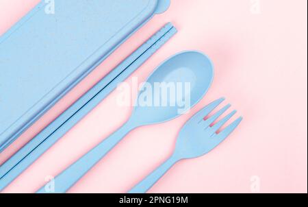 Set aus Löffeln, Gabeln und Essstäbchen aus Kunststoff auf pinkfarbenem Hintergrund. Stockfoto
