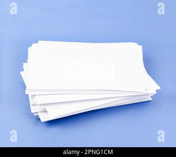 Stapel leerer A4-Blätter auf blauem Hintergrund. Stockfoto