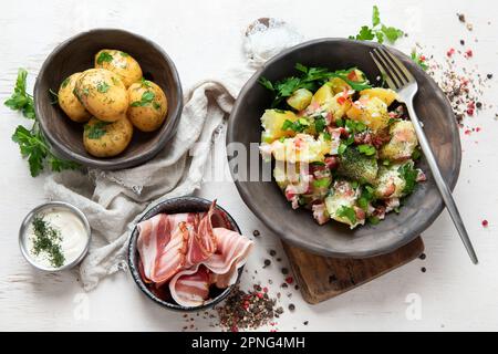 Schüssel mit warmem Kartoffelsalat mit Speck auf weißem Hintergrund. Draufsicht. Stockfoto