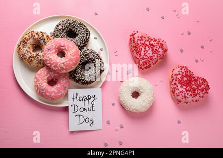 Donuts-Donuts mit Schokolade, Marshmallow und Zuckerstreuseln auf pinkfarbenem Hintergrund, Draufsicht. Farbenfrohe Karneval- oder Geburtstagskarte. Fröhliche Nationa Stockfoto