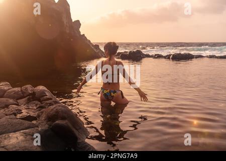 Sonnenuntergang auf der Insel El Hierro. Kanarische Inseln, Touristenfrau, die im natürlichen Becken von Charco Azul badet Stockfoto