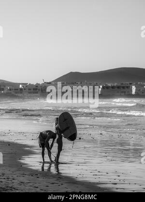 Schwarzweißfotografie, Surfer am Strand, Playa Famara, Lanzarote, Kanarische Inseln, Spanien Stockfoto